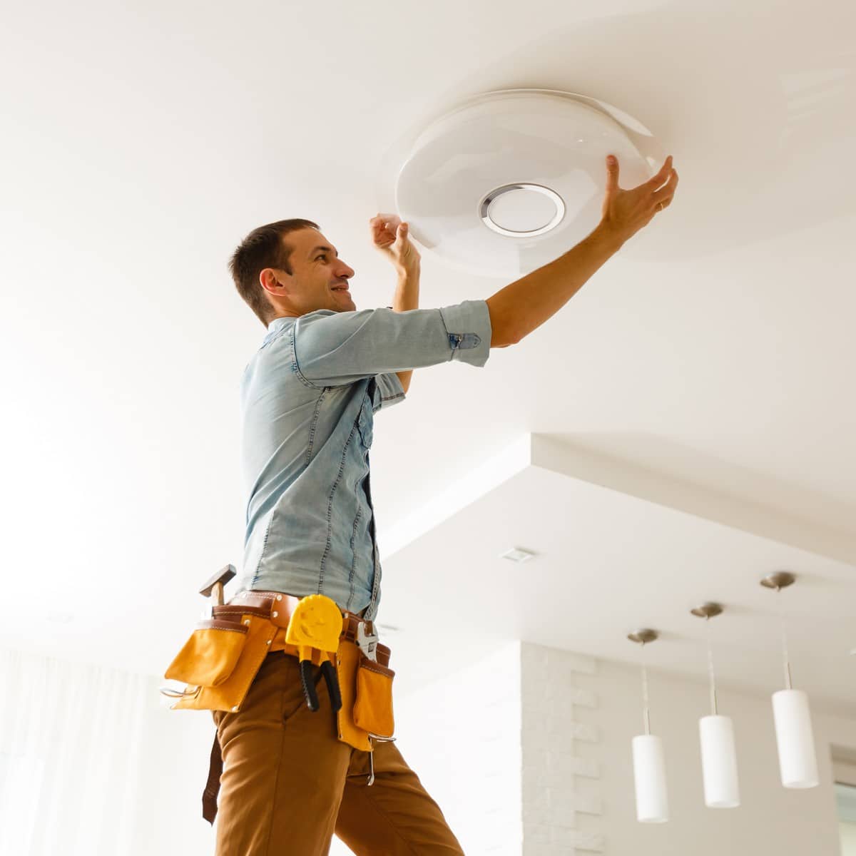 Electrician is installing and connecting a lamp to a ceiling.